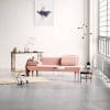 Modern pink sofa in minimalist interior with wooden table and decorative items, showcasing stylish home design.