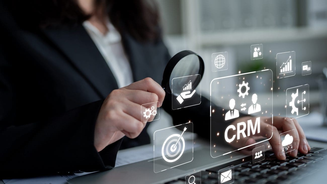 Business professional using a laptop with CRM icons and features, symbolizing customer relationship management, data organization, and sales automation.