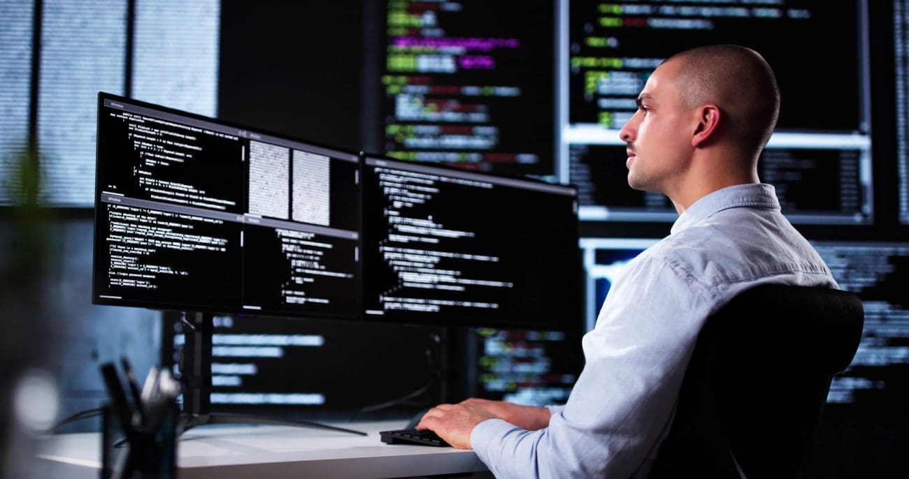 Web developer coding on dual monitors with programming text, illustrating SEO-friendly web development processes.