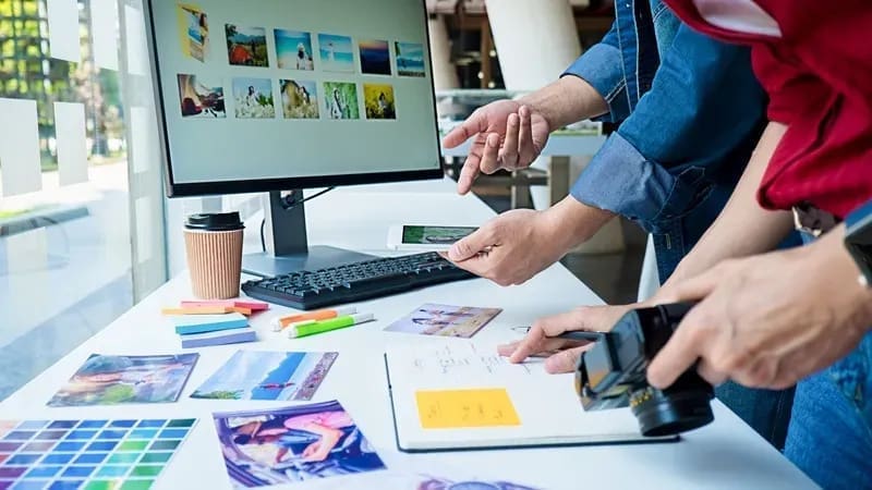 Creative workspace with people reviewing photos and color swatches on a desk.